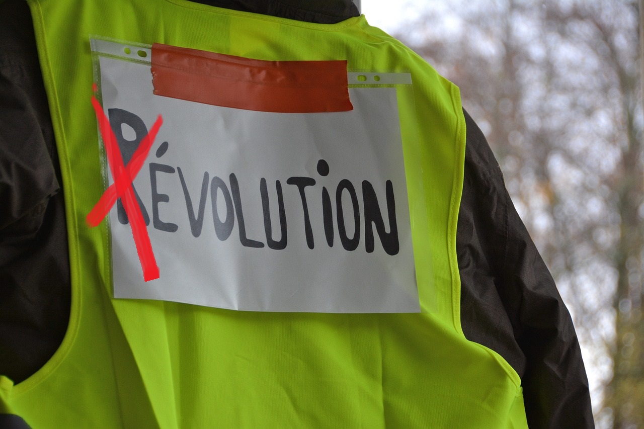 Gilets jaunes portant une affiche avec le mot révolution et le r barré en rouge